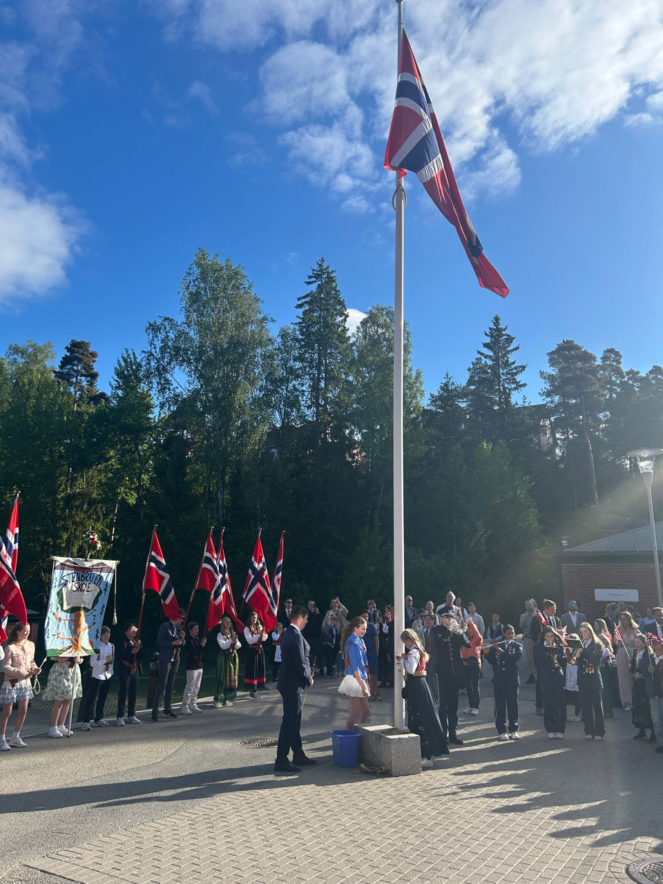En gruppe mennesker som står foran en flaggstang med flagg