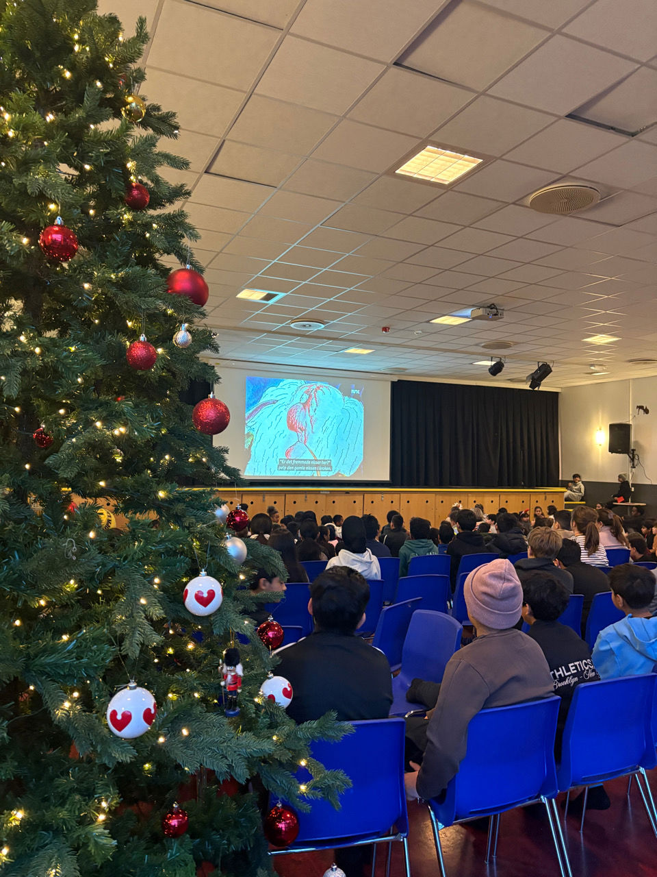 En gruppe mennesker som sitter i stoler i et rom med et juletre