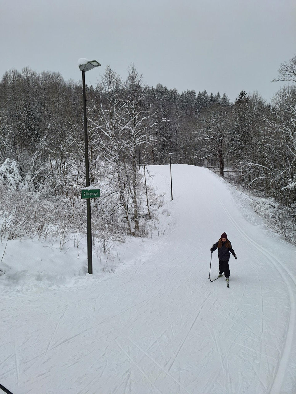 en person som står på ski nedover en snødekt vei