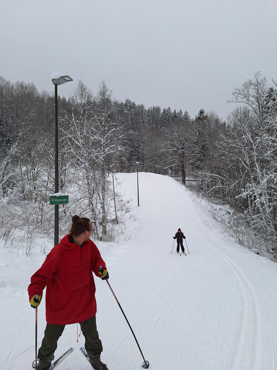 et par personer som står på ski ned en snødekt vei