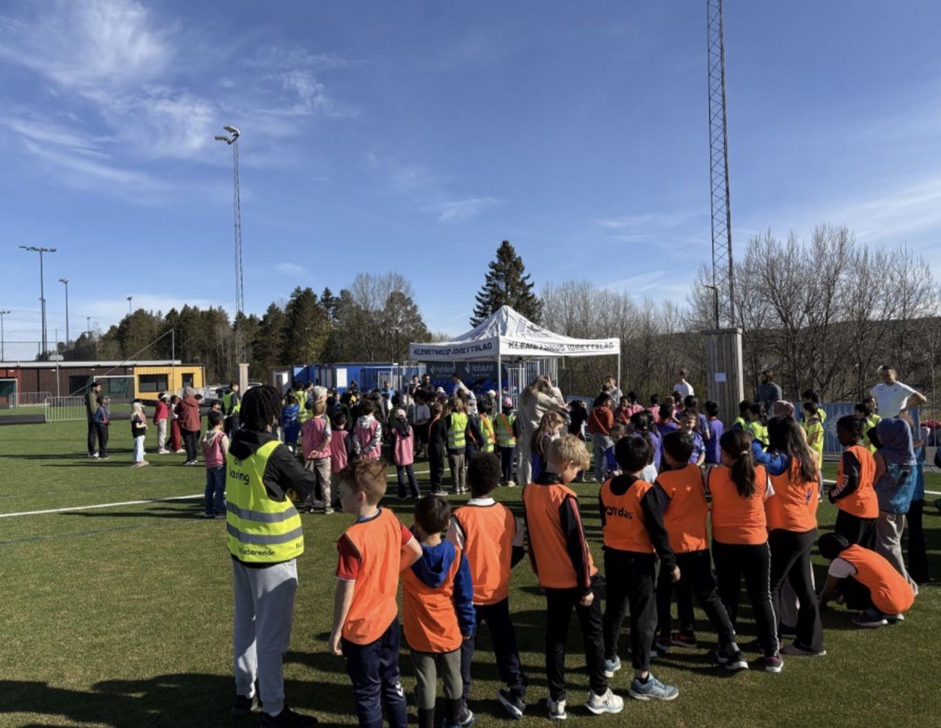 En gruppe mennesker i oransje vester står på et jorde