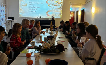 en gruppe mennesker som sitter ved et bord med mat og drikke