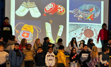 en gruppe mennesker som står i et rom med en stor skjerm