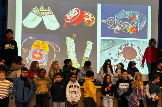 en gruppe mennesker som står i et rom med en stor skjerm