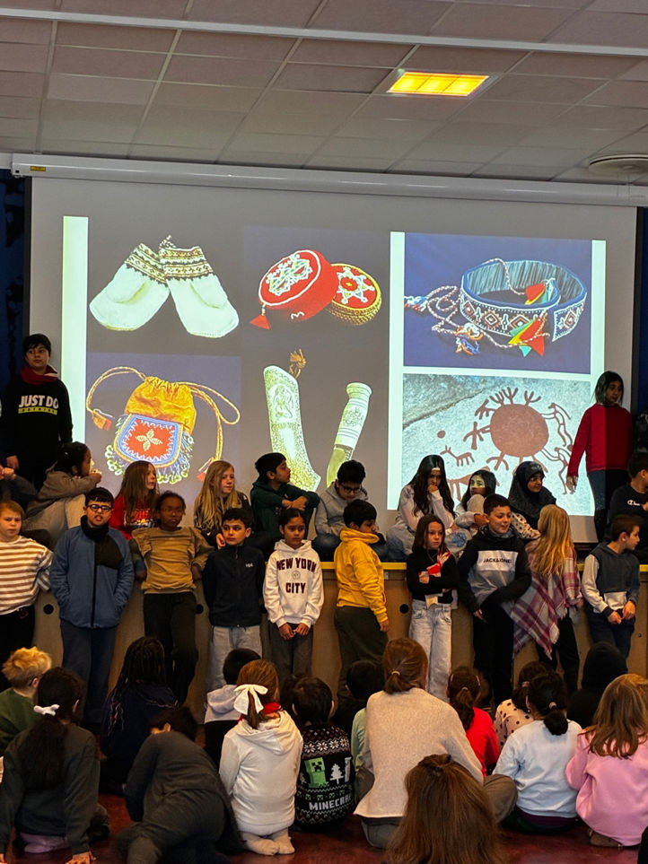 en gruppe mennesker som står i et rom med en stor skjerm